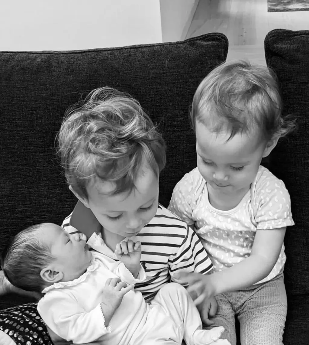 Siblings meeting newborn baby